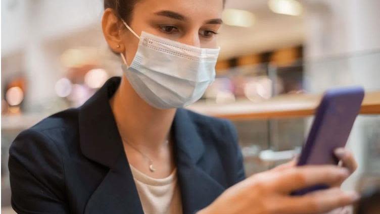 Person wearing mask using phone
